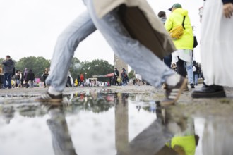Festival-goers jump over a puddle of rain at the Lollapalooza Festival in the Olympic Stadium and