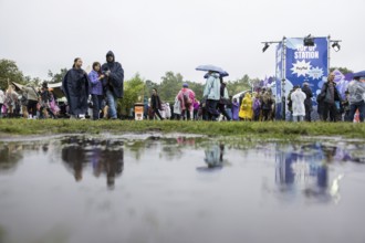 Festival-goers reflected in a puddle at the Lollapalooza Festival in the Olympic Stadium and on the