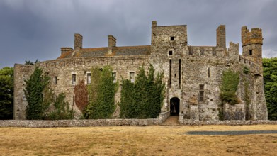 View of a stone castle with ivy and clouds in the sky, Pirou Castle in Normandy, France