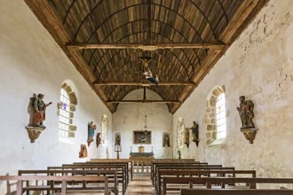 Interior view of a chapel with wooden ceiling, benches and statues on the walls, Pirou Castle in