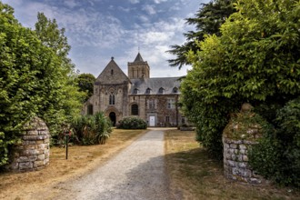 Historic church with a path surrounded by green trees and blooming nature, The Abbey de La Lucerne