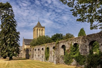 A church tower and a historic stone wall surrounded by trees in summer weather, The Abbey de La