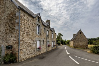 Traditional stone house on a quiet village street under a cloudy sky, Historic houses in Normandy,