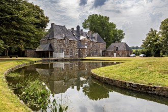 A castle with a moat in a green setting, surrounded by trees and clouds in the sky, The Abbey of La