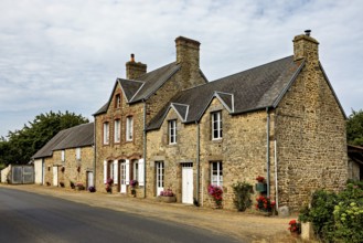 Historic stone houses along a village street with flowering windows, Historic houses in Normandy in