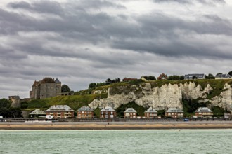 Castle on cliffs with houses on the beach, dramatic sky over coastal landscape with sea view,
