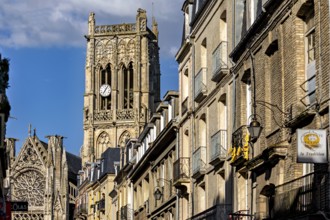 Gothic cathedral with impressive bell tower and stone architecture along the street under a blue