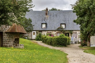 Idyllic farmhouse with garden and gravel path surrounded by green meadows, the historic mill