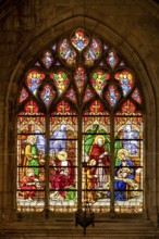 A Gothic stained glass window shows a religious scene with the Holy Family and angels in bright