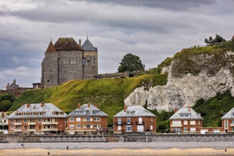 Historic castle on cliffs with modern houses below, under a cloudy sky, sea view, Dieppe Castle in