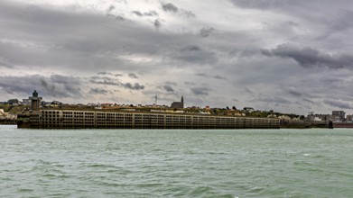 Massive harbour wall under a cloudy sky, surrounded by the sea in a stormy atmosphere, The harbour