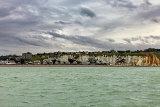 Rocky coast with houses above, under a cloudy sky, The coast of Dieppe in Normandy, France