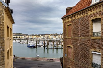 View of a harbour with boats through two brick buildings in the foreground, The harbour of Dieppe
