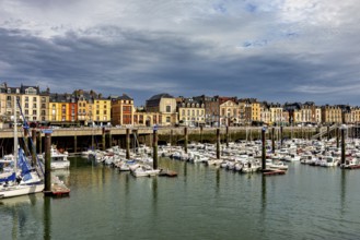 Historic buildings line a harbour full of boats under a cloudy sky, The harbour of Dieppe in