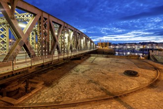 Metal bridge in evening city with illuminated sky and cloudy horizon, The swing bridge of Dieppe in