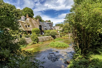 Half-timbered house in the middle of an idyllic landscape with a flowing stream and lush greenery,