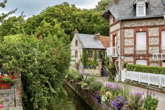 Narrow alley with brick houses and flowering canal, surrounded by rural nature, The historic mill