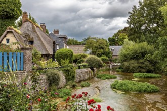 Romantic river landscape with cottages and blooming flowers under a cloudy sky, the historic mill