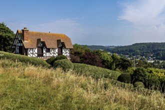 A half-timbered house on a hill surrounded by meadows and forests under a blue sky, Historic
