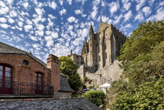 View of an imposing medieval castle against a cloudy sky, surrounded by green trees and old