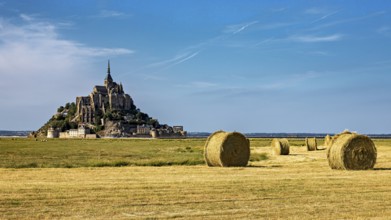 View of Mont Saint-Michel with bales of straw in a field under a clear sky, Mont Saint Michel in