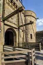A massive medieval Tor tor with chains and stone walls under a clear sky, Mont Saint Michel in