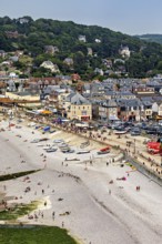 Beach scene in a coastal town with many people and boats, Etretat in Normandy, France