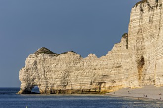 High cliffs form the coastline, overlooking a calm beach with clear skies, The cliffs and alabaster
