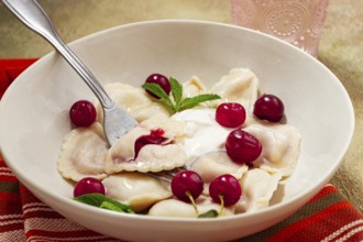Traditional dumplings with cherries and yogurt, close-up, no people