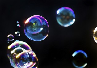 Iridescent soap bubbles in the colours of the rainbow against a black background, Recklinghausen,