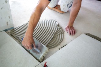Tile laying: Tiler lays large light-coloured floor tiles