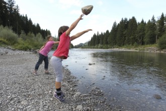 Girls, children throwing stones into a river, activity with children in nature, Allgäu, Bavaria,
