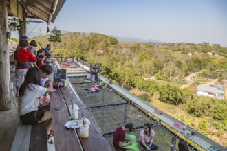 Customers eat, drink and relax on a net suspended over the hillside at the Akha Cottage restaurant