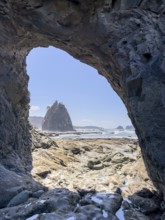 Large rock with a hole and people in the foreground, Hole in The Wall, Rialto Beach, Olympic