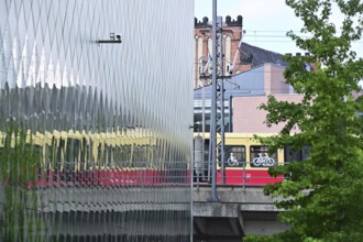 A suburban railway is reflected in the façade of the Futurium in Berlin-Mitte