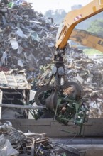 Hydraulic crane lifts scrap metal at the scrap yard