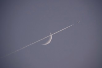 Evening sky with crescent moon and aeroplane, Germany