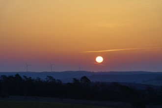 Landscape with sunrise over silhouettes of wind turbines on the horizon, Sodenberg, Hammelburg,