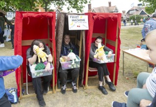 Three women forming human fruit machine game at village summer fete, Bawdsey, Suffolk, England, UK