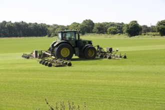 John Deere tractor mowing grass turf field, Butley, Suffolk, England, UK