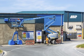 Man on cherry picker machinery cleaning sign, Port of Teignmouth, Teignmouth, south Devon, England,