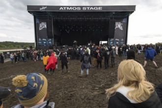 Festival visitors dance in the mud in front of the Atmos Stage at the Rock am Ring Festival on