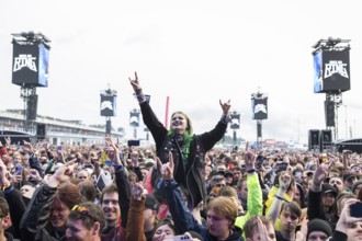 Festival visitor on shoulders with a French fries fork shaped like a hand at the Rock am Ring