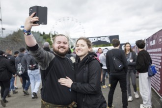 Festival visitors Kevin and Jenny take a photo in front of a container with the Rock am Ring logo