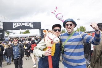 Two festival visitors with their inflatable animals Charles and Chantal in front of a container