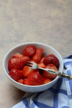 Sliced strawberries in hull with fork, Fragaria