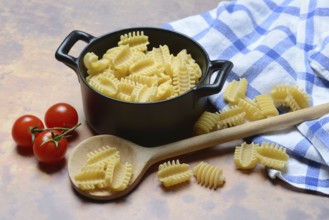 Italian pasta, Radiatori variety, in pots and wooden spoon