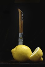 Lemon with knife in front of black background