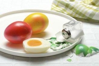 Easter eggs and salt shaker on plate, partially peeled