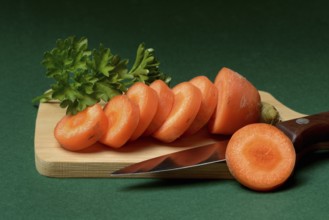 Carrot, carrot slices with kitchen knife on wooden board